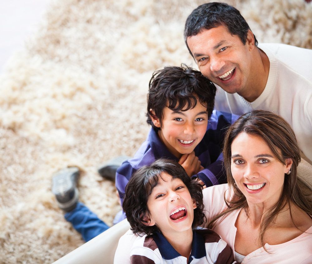 A family comprised of a father, a mother, and two boys is looking happily upward.
